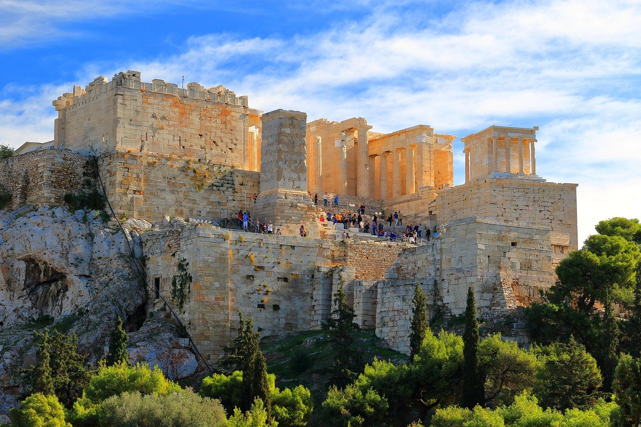 Antika Akropolis i Aten med historiska stenstrukturer och turister under en klarblå himmel