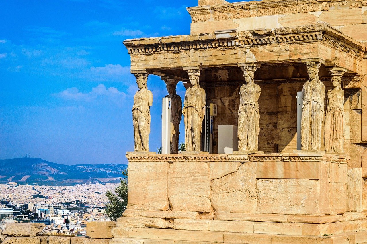 Antika grekiska Erechtheion-templet med karyatider som blickar ut över Atens stad och blå himmel