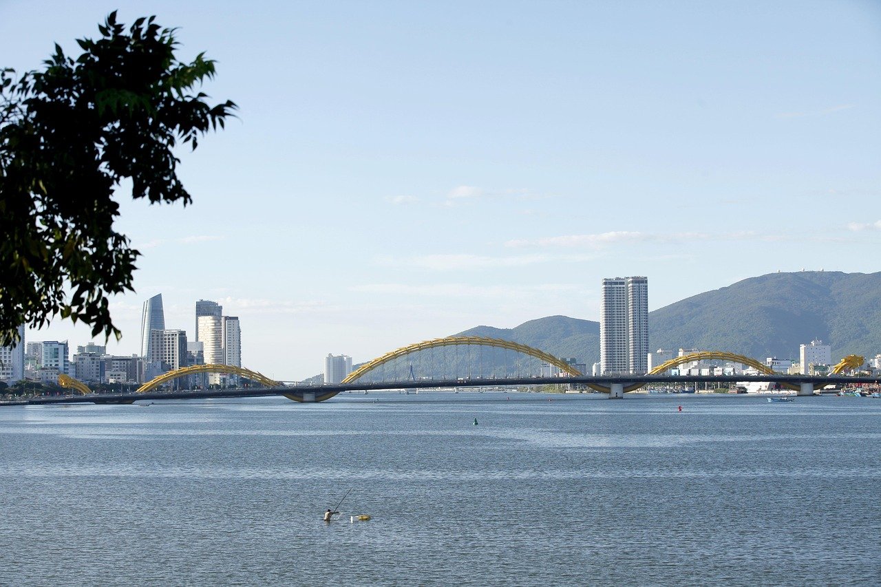 Scenisk vy över Drakbron över Hanfloden med stadssilhuett och berg i Da Nang, Vietnam under klarblå himmel