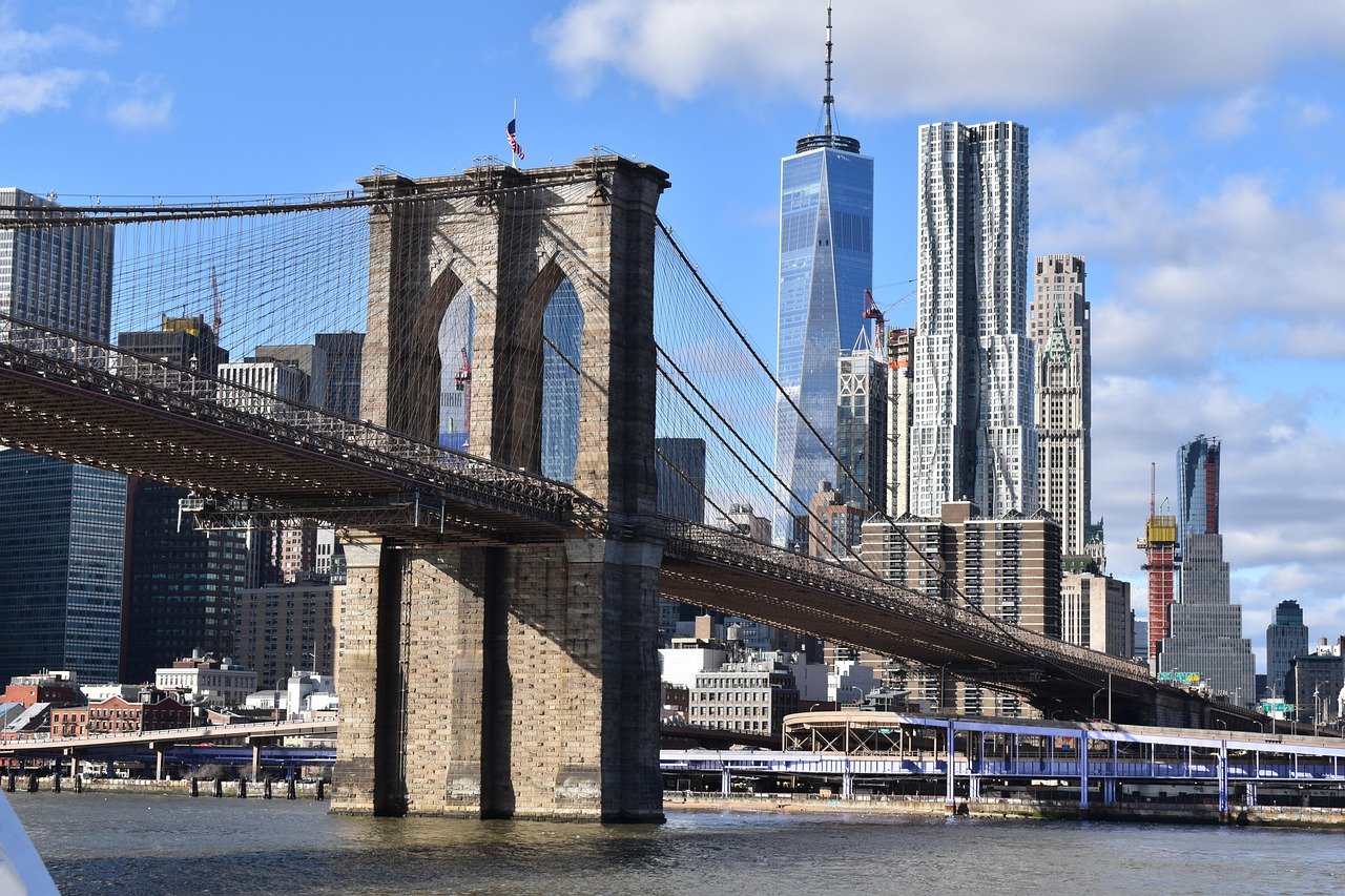 Brooklyn Bridge som sträcker sig över East River med Manhattans skyline och One World Trade Center i bakgrunden på en klar dag