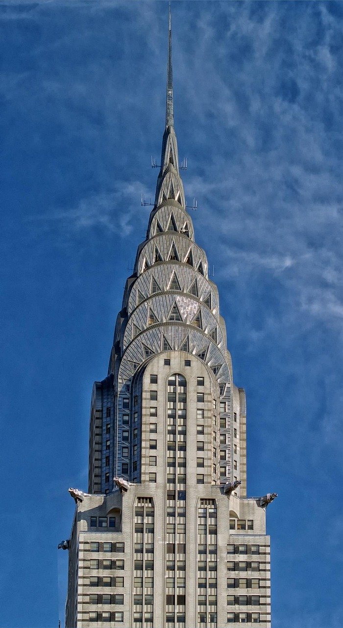 Närbild av den ikoniska Chrysler Building-spiran med sin Art Deco-arkitektur mot en blå himmel