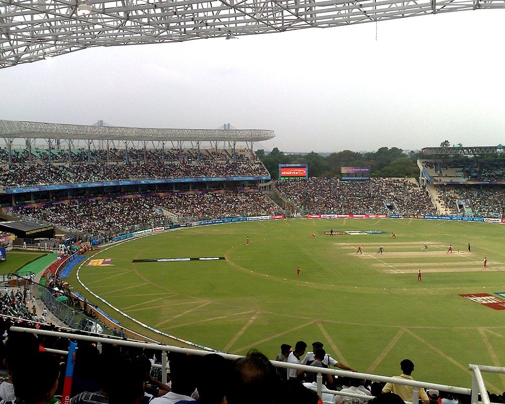 Cricketstadion fyllt med åskådare under en live cricketmatch på en molnig dag
