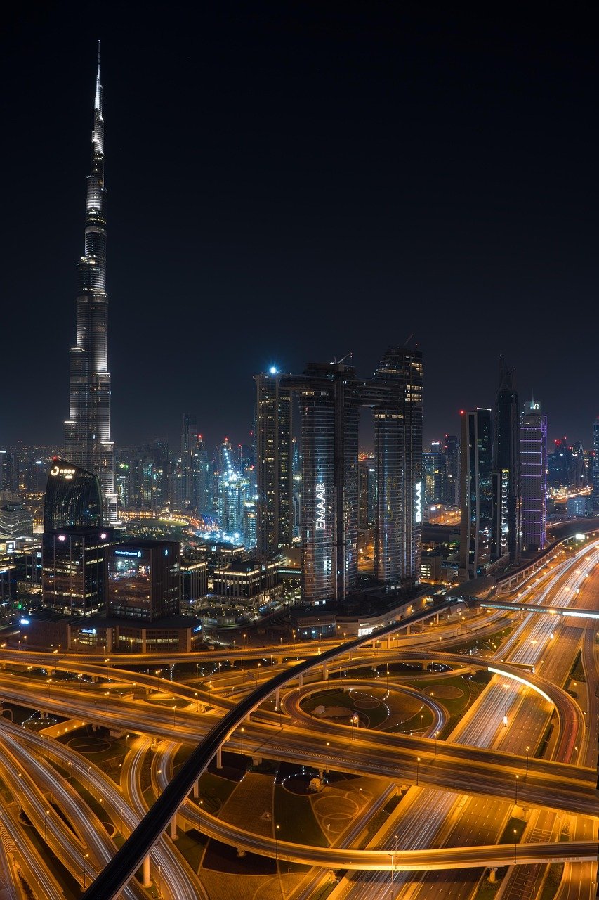 Nattvy över Dubais stadsskyline med upplyst Burj Khalifa och livlig motorvägskorsning med ljusspår