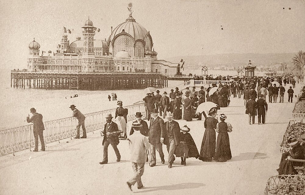 Viktoriansk strandpromenad med utsmyckad pirpaviljong Vintagefoto av viktorianska människor som promenerar på en strandpromenad nära en stor utsmyckad pirpaviljong