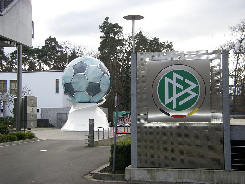 Fotbollsskulptur vid det tyska fotbollsförbundets huvudkontor Stor fotbollsskulptur utanför det tyska fotbollsförbundets huvudkontor med modern byggnad och träd