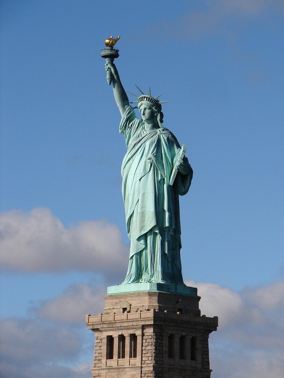 Frihetsgudinnan i New York City med klar blå himmel i bakgrunden, ikonisk symbol för frihet och demokrati i USA
