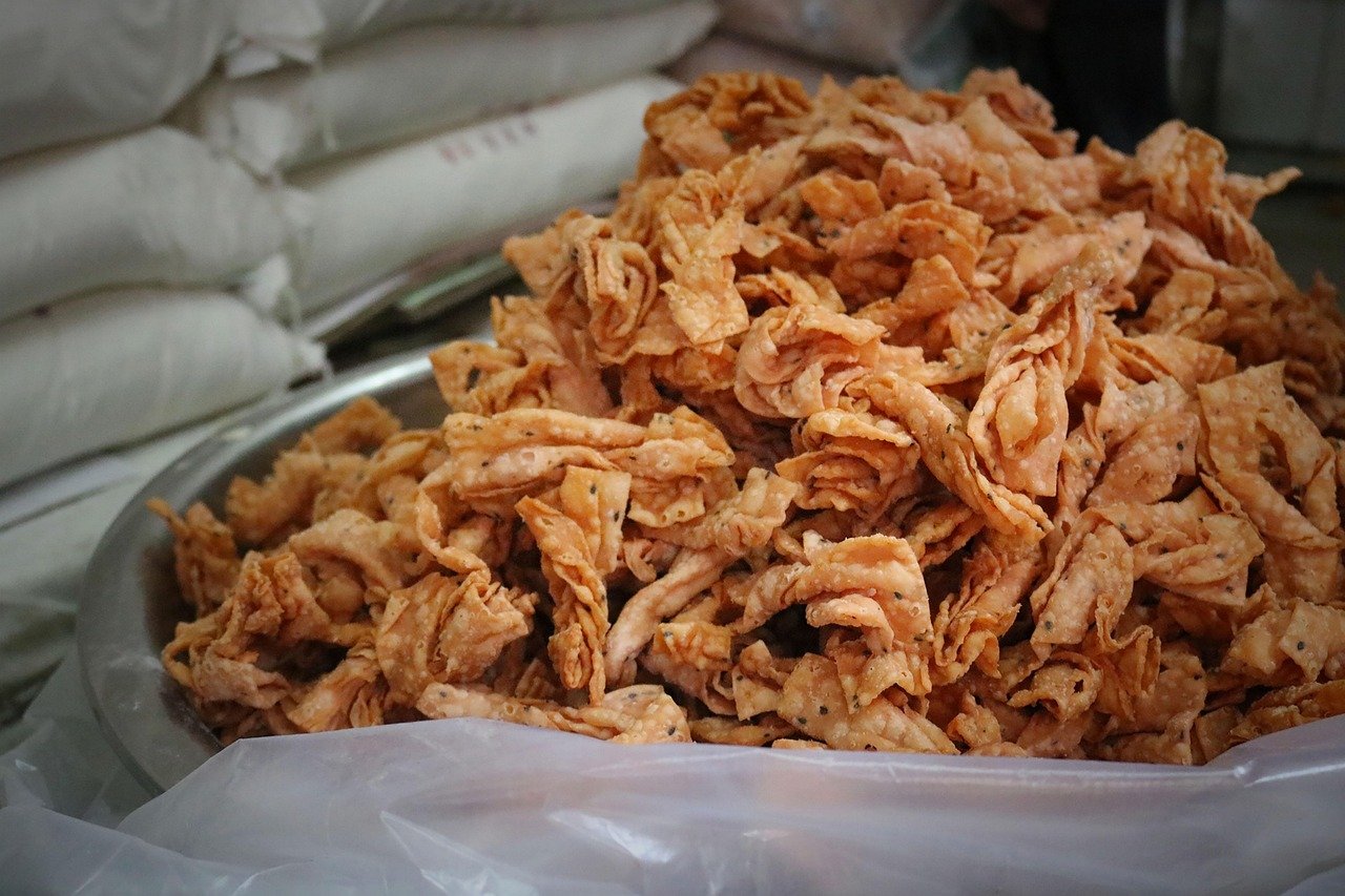 Närbild av en stor skål fylld med krispiga indiska snacks kallade karanji eller gujiya, gjorda av friterad deg med kryddor.