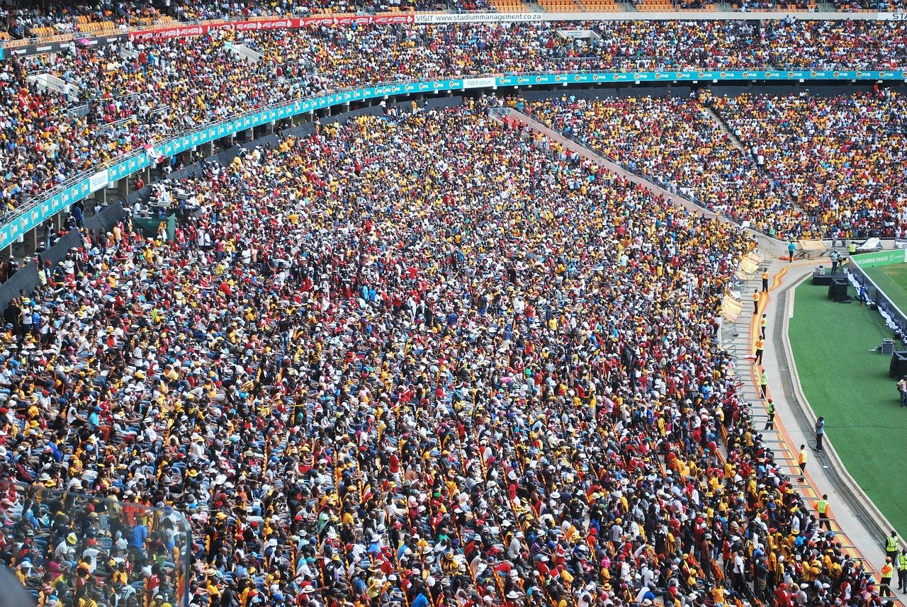 Stor publik av åskådare på en stadion under ett sportevenemang med livliga färger och fullsatta platser