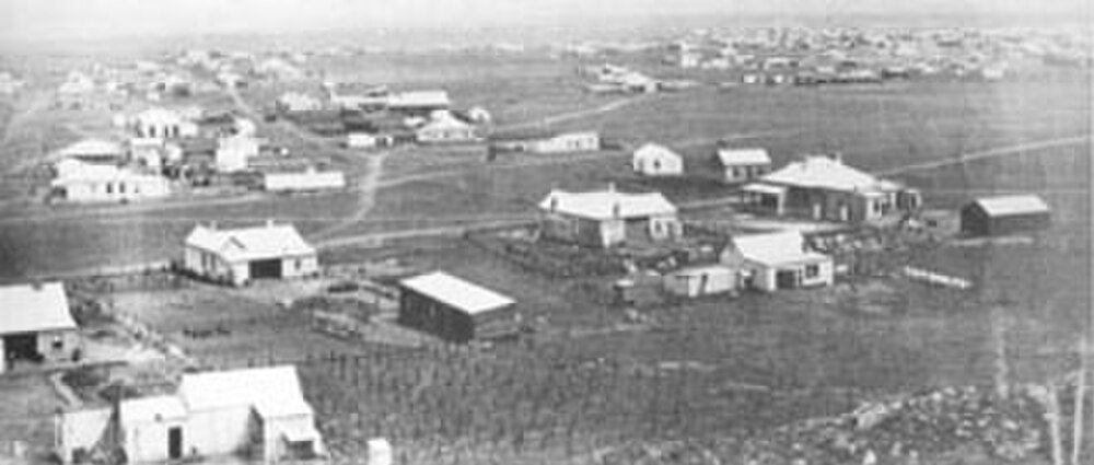 Flygfoto av lantlig by och hus Flygfoto av en liten lantlig by med spridda hus och öppna fält, som visar tidiga bosättningsmönster.