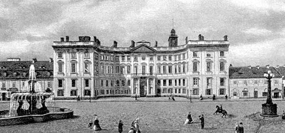 Historiskt europeiskt palats med fontän och människor Historiskt svartvitt foto av ett storslaget europeiskt palats med en fontän och människor i tidstypiska kläder på torget