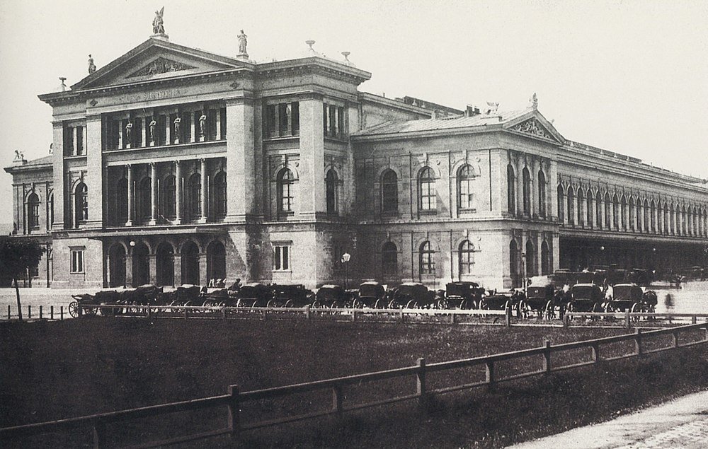 Historisk byggnad med hästdragna vagnar Historiskt svartvitt foto av en stor klassisk byggnad med hästdragna vagnar parkerade utanför