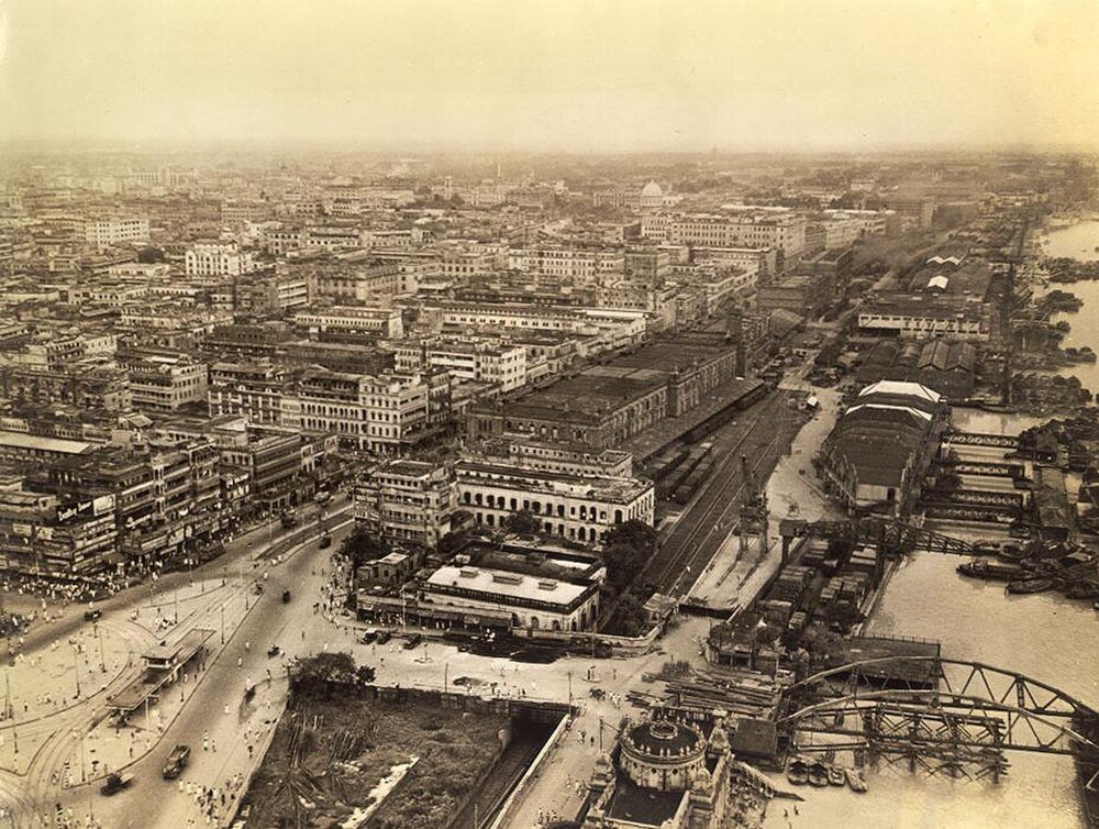 Historisk flygfoto av stadsbild med flod och broar Flygfoto av en historisk urban stadsbild med täta byggnader, vägar och en flod med broar och båtar.