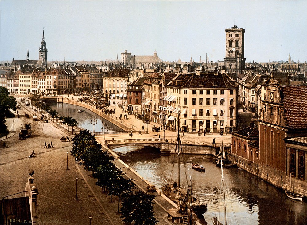 Historisk Köpenhamns stadsbild med kanaler och gamla byggnader Historisk vy över Köpenhamns stad med kanaler, broar, gamla byggnader, båtar och människor som promenerar längs vattnet i Danmark