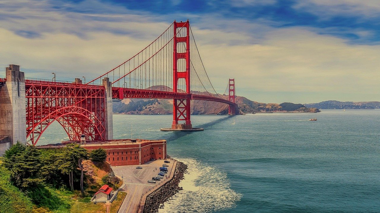 Golden Gate Bridge i San Francisco som sträcker sig över det blå vattnet med klar himmel och avlägsna kullar