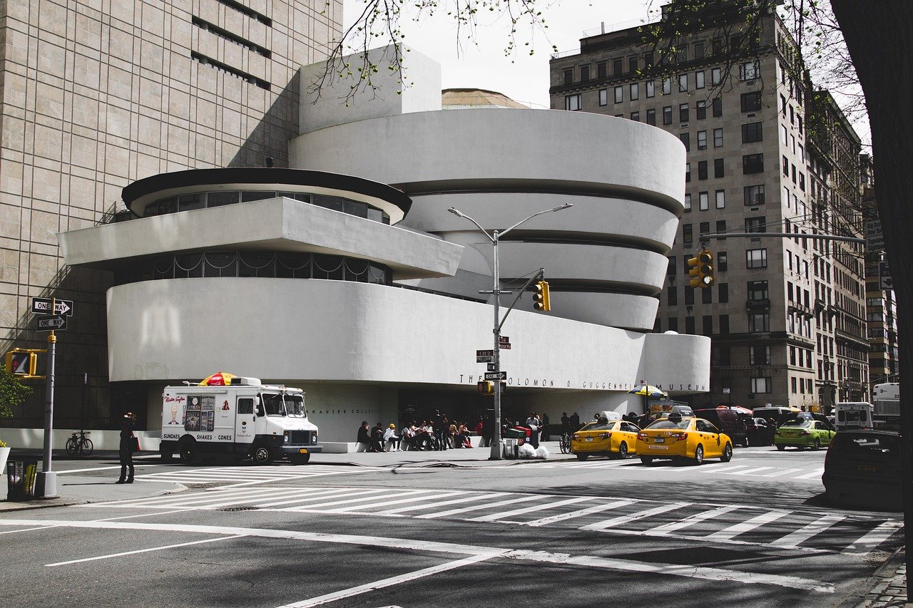 Exteriör vy av Solomon R. Guggenheim Museum i New York City med gula taxibilar och en glassbil i närheten