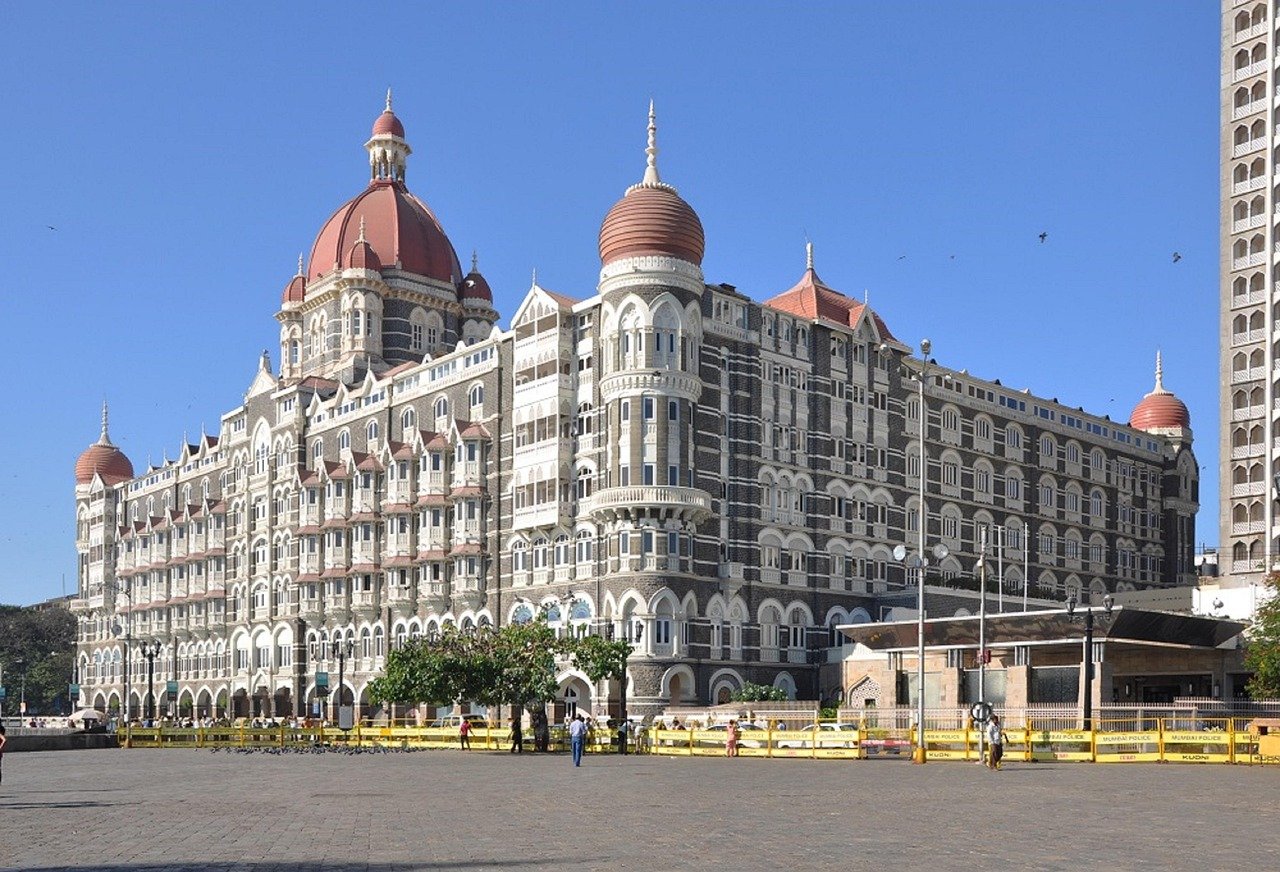 Det ikoniska Taj Mahal Palace Hotel i Mumbai med sina distinkta kupoler och kolonial arkitektur under en klarblå himmel