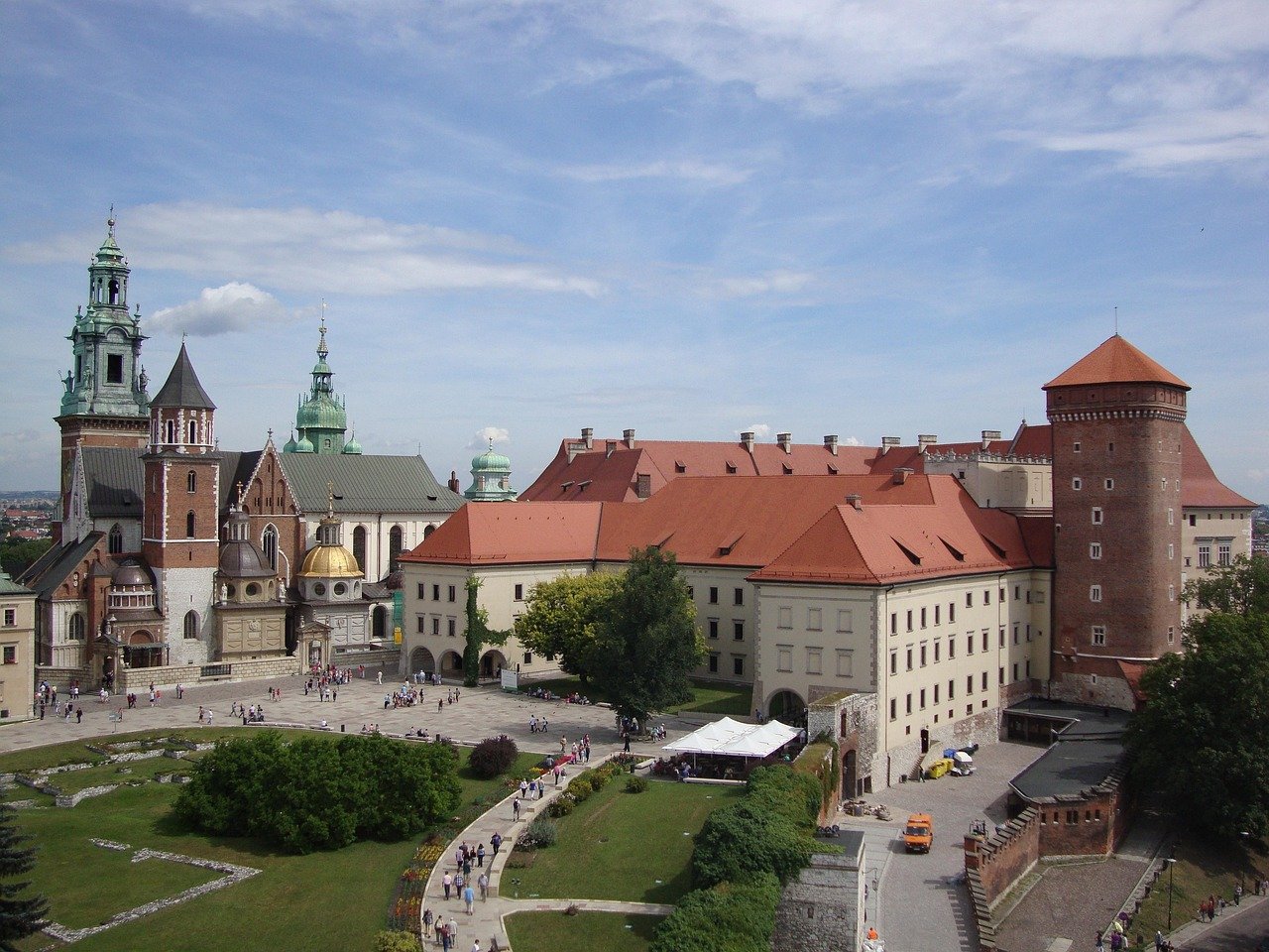 Historiska Wawel-slottet med röda tak och katedralstorn i Krakow, Polen, populär turistdestination med trädgårdar och gångvägar.
