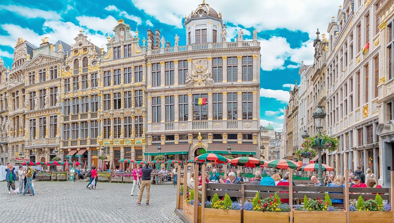 Historiska Grand Place torget i Bryssel med utsmyckade gilles hus, uteserveringar och människor som njuter av en solig dag