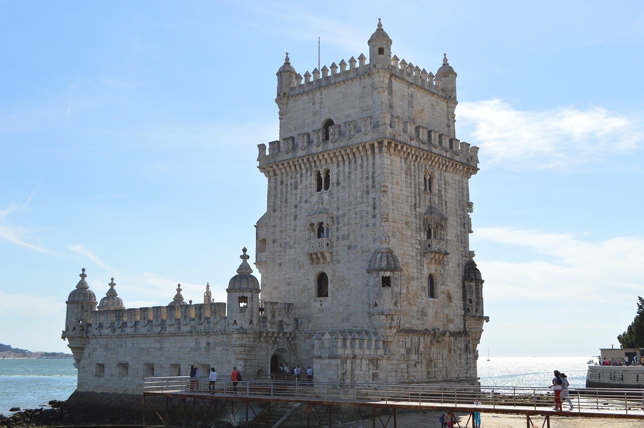 Historiska Belem-tornet i Lissabon Portugal på en solig dag vid Tajo-floden med turister som promenerar i närheten
