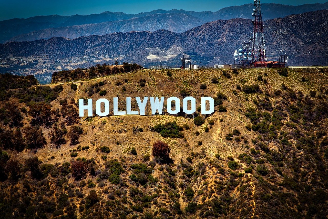Ikonisk Hollywoodskylt på en solig kulle med berg i bakgrunden, symboliserar underhållningsindustrin i Los Angeles