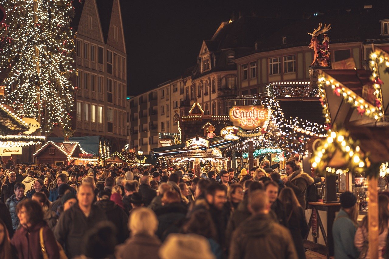 Trång julmarknad på natten med festliga ljus, dekorerade stånd och människor som njuter av julshopping och firande