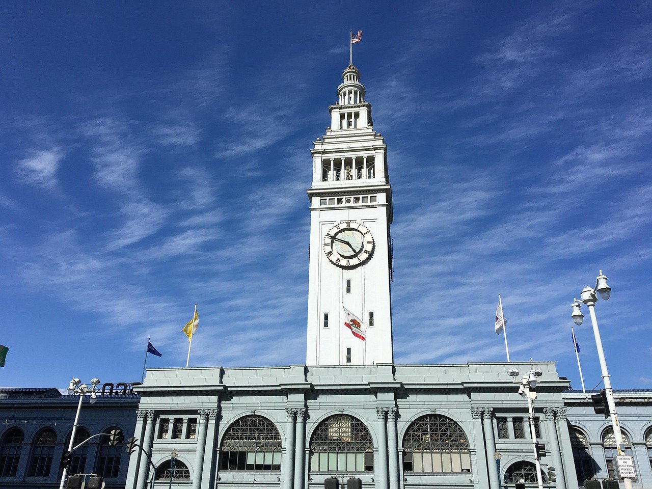 Historiska San Francisco Ferry Building med klocktorn under klarblå himmel och amerikansk flagga på toppen