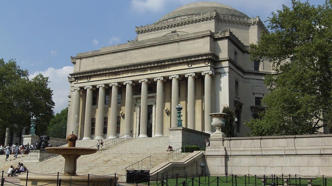 Den ikoniska biblioteksbyggnaden vid Columbia University med stora kolonner och trappor under en klar himmel i New York City