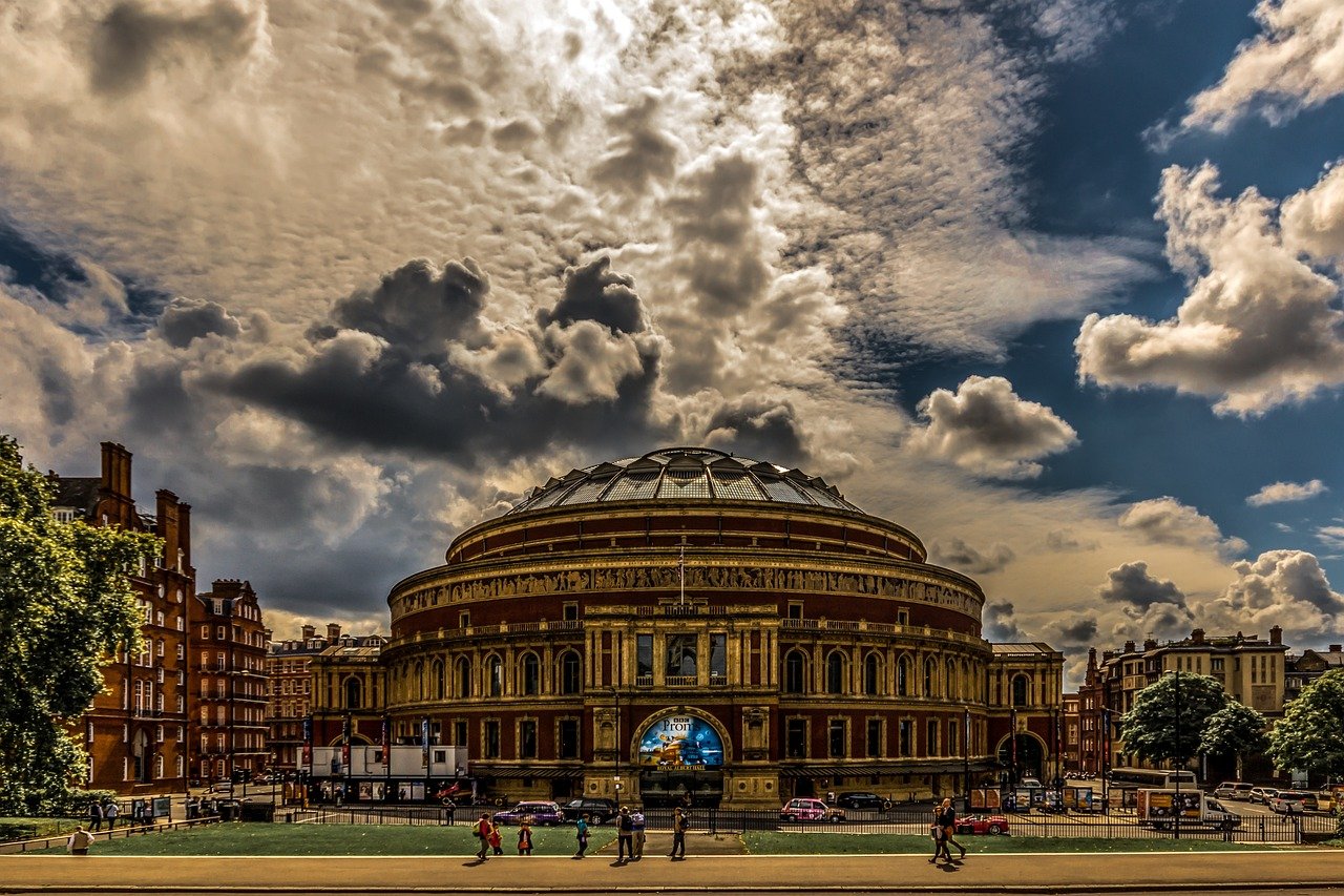 Royal Albert Hall i London med dramatiskt molnig himmel och människor som går framför, historisk konsertlokal och landmärke
