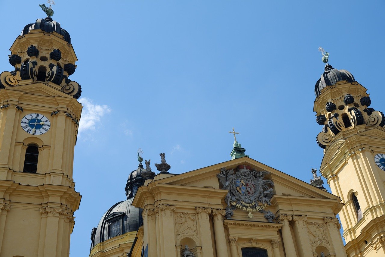 Barockstil gula kyrktorn med klockor och utsmyckade detaljer under klarblå himmel