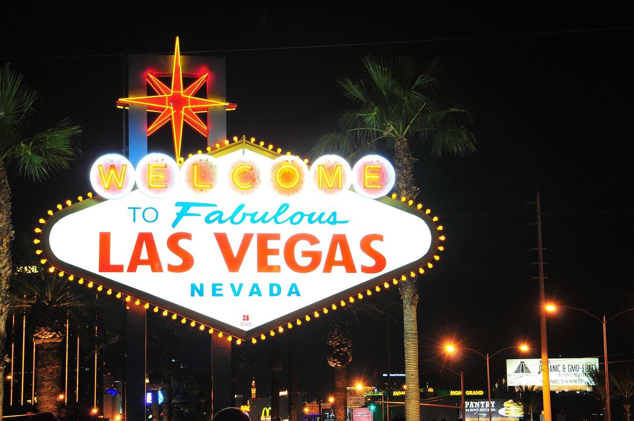 Ikonisk Välkommen till Fabulous Las Vegas Nevada neonskylt på natten med palmer och stadsljus i bakgrunden