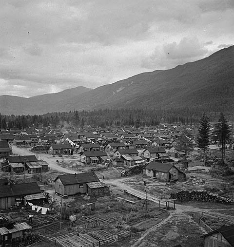 Historisk lantlig by med trähus och berg Historiskt svartvitt foto av en liten lantlig by med trähus och bergslandskap i bakgrunden