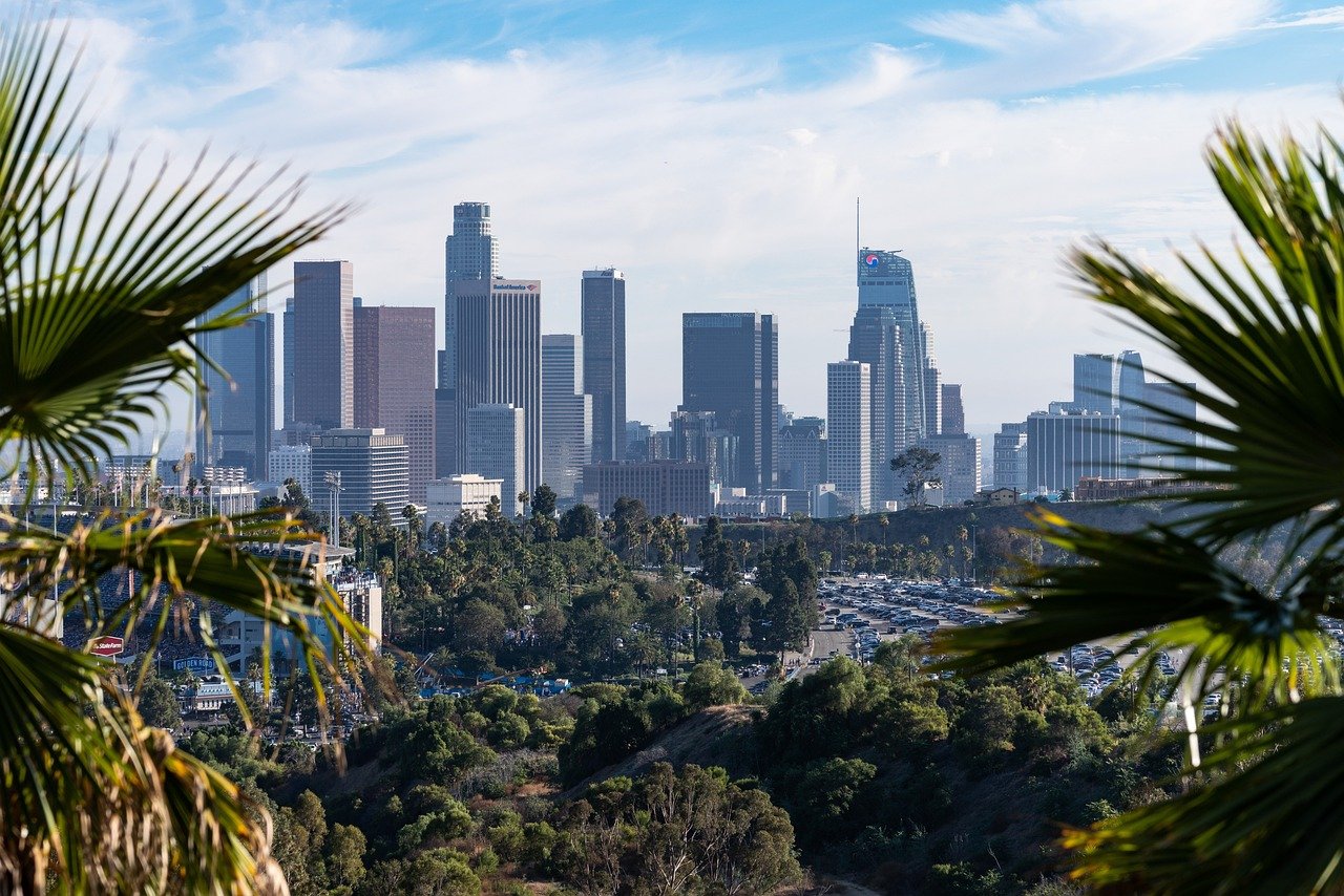 Downtown Los Angeles skyline med höga byggnader, palmer och klarblå himmel i Kaliforniens stadsbild