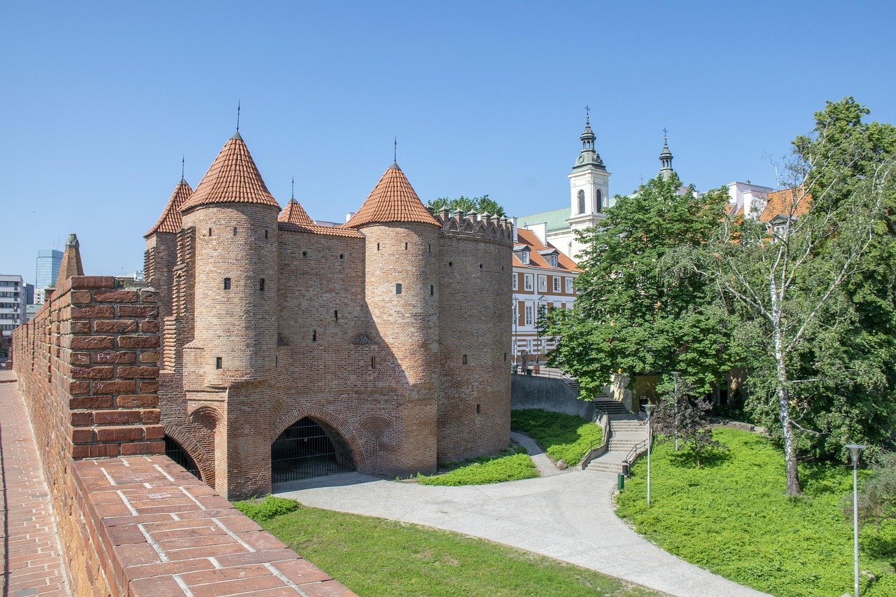 Historisk tegelbarbikanfästning med koniska tak och stadspark i Warszawa, Polen under klarblå himmel