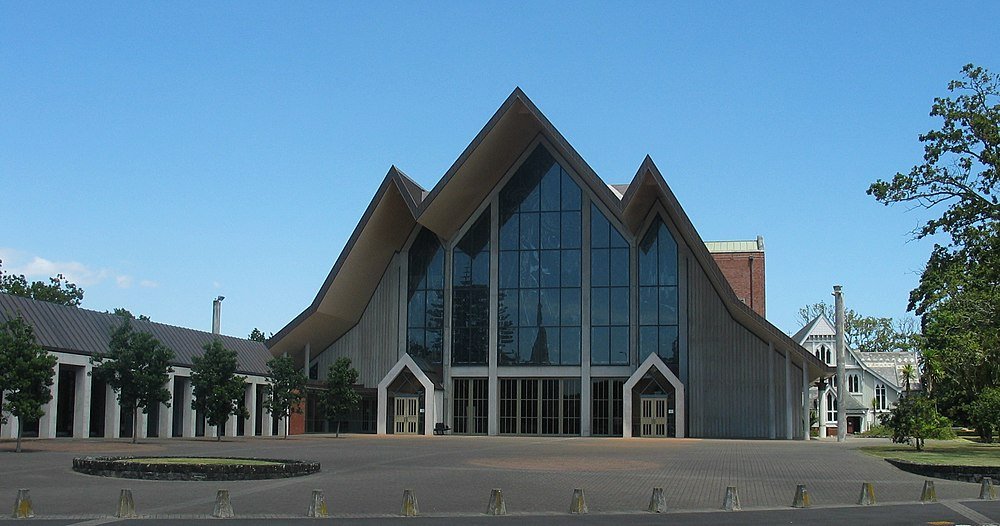 Modern kyrka med vinklat tak och glasfasad Modern kyrkobyggnad med stora glasfönster och unik vinklad takdesign under klarblå himmel