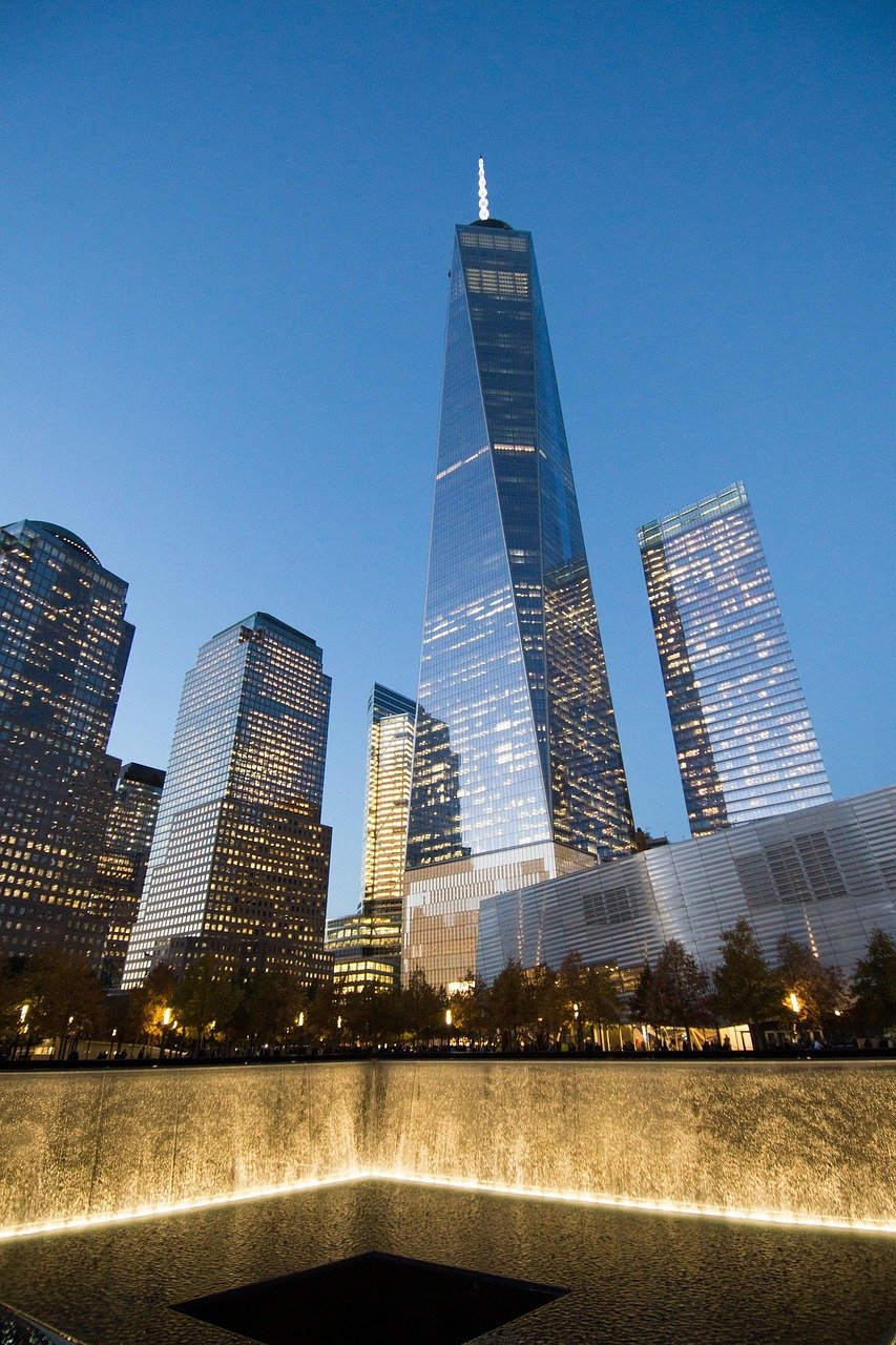 One World Trade Center och 9/11 Memorial som reflekterar i vatten i skymningen i New York City skyline