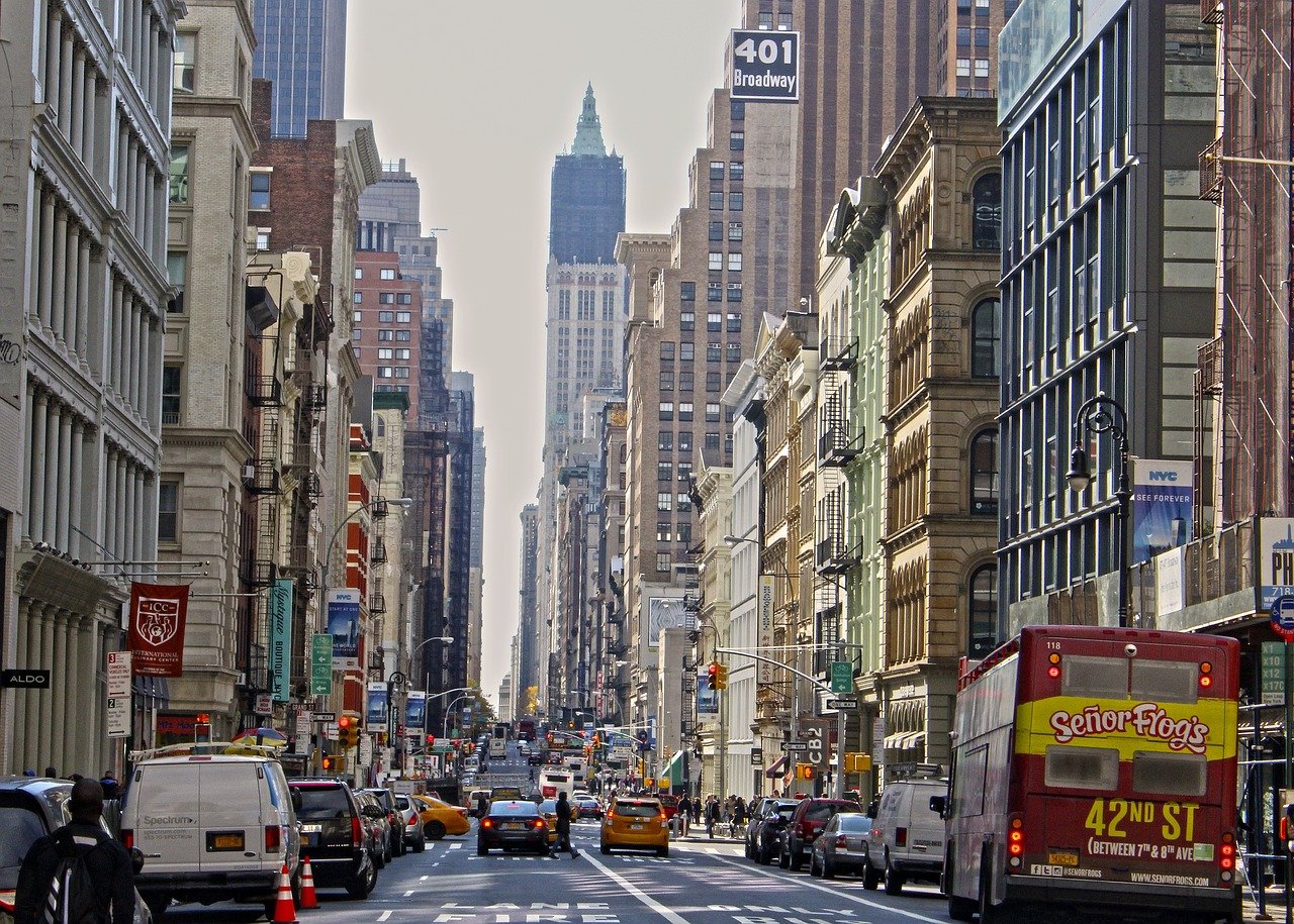 Livlig gata i New York City med gula taxibilar, höga byggnader och en röd buss som annonserar Señor Frog's på 42nd Street