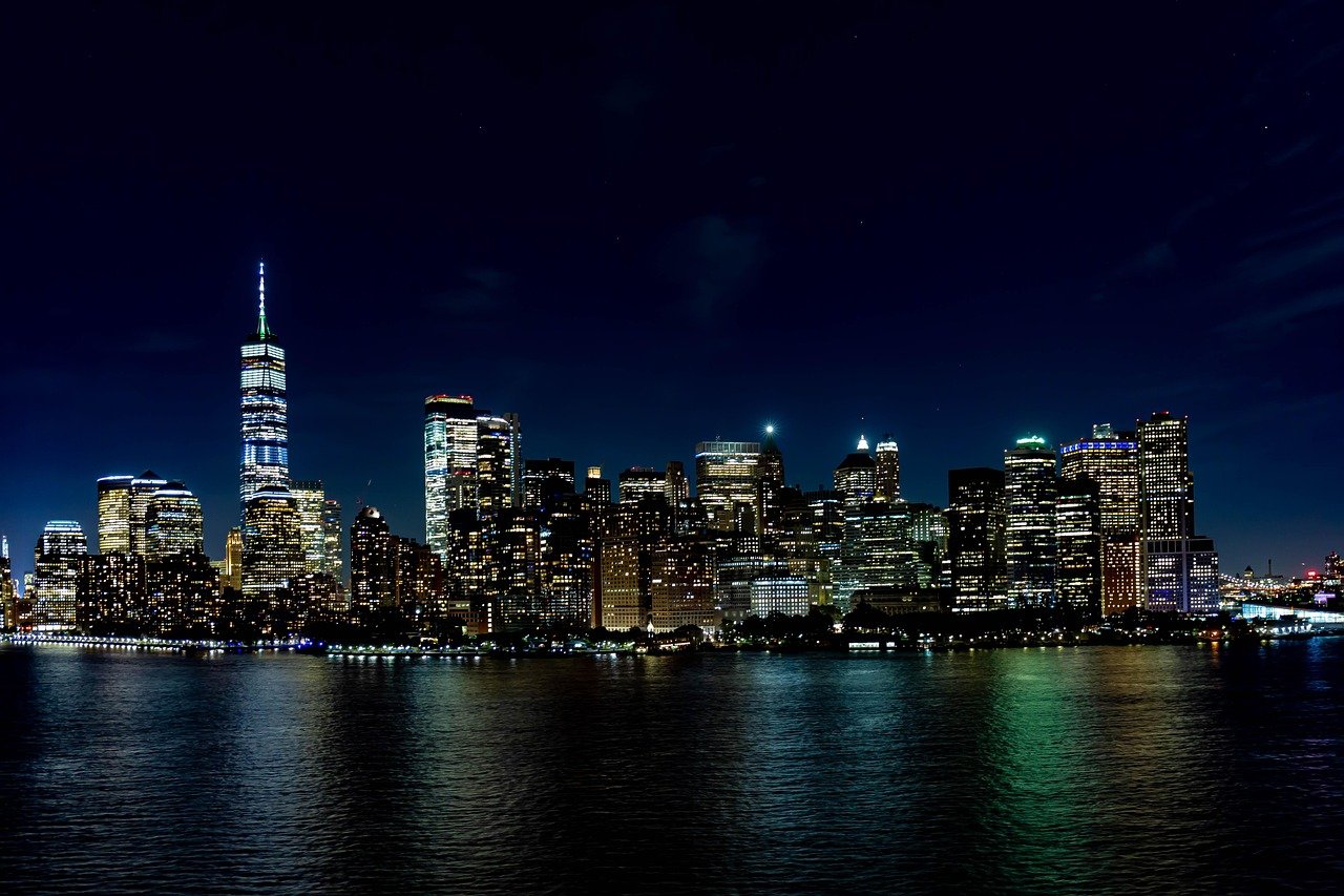 Nattvy av New York Citys skyline med upplysta skyskrapor och reflektioner på vattnet