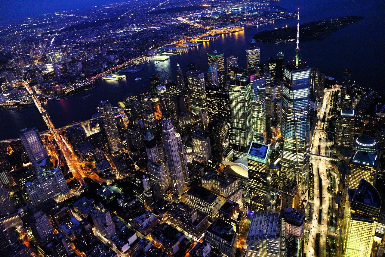 Flygvy på natten av New York Citys skyline med upplysta skyskrapor och broar över Hudsonfloden