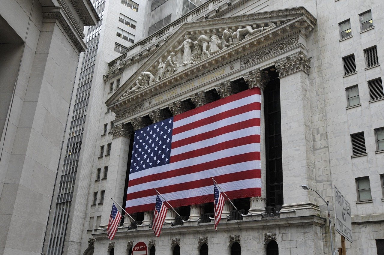 Frontal vy av New York Stock Exchange-byggnaden prydd med stor amerikansk flagga och mindre flaggor