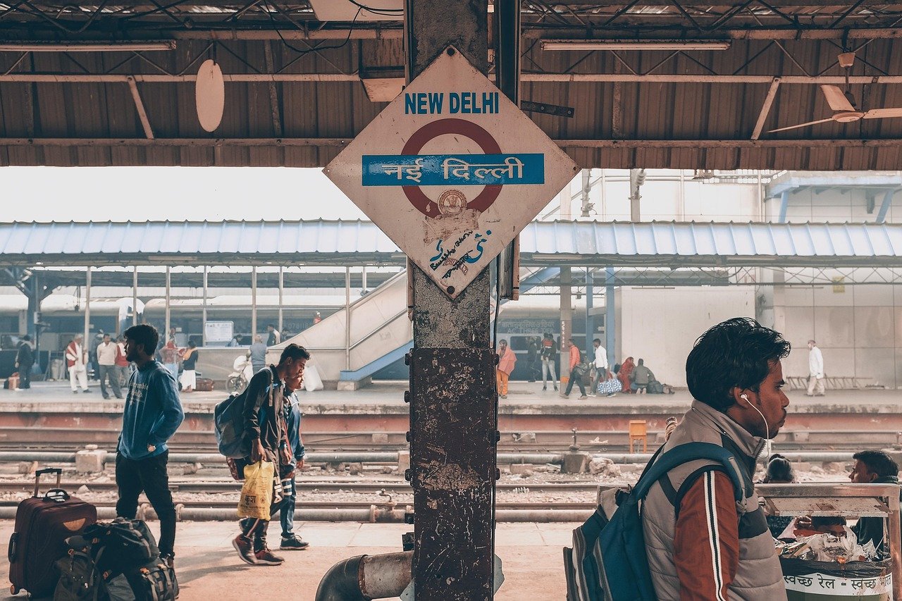New Delhi järnvägsstation plattform med passagerare som väntar och går, som visar upptagen tågresa i Indien