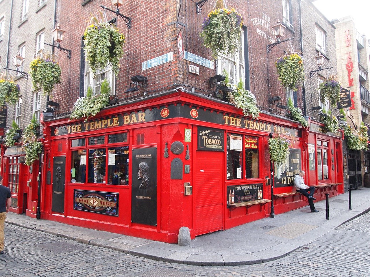 The Temple Bar Dublin ikoniska röda pub med hängande blomkorgar och kullerstensgatuhörn