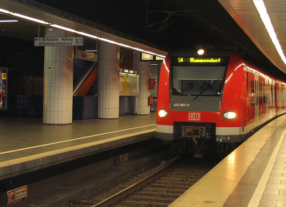 Rött DB S-Bahn-tåg på tysk tunnelbanestation Rött DB S-Bahn-tåg anländer till en tysk tunnelbanestation med skyltar på tyska