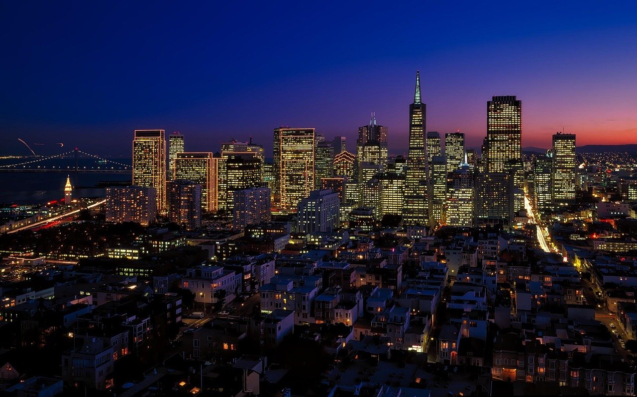 San Franciscos stadssilhuett i skymningen med upplysta skyskrapor och Bay Bridge i bakgrunden