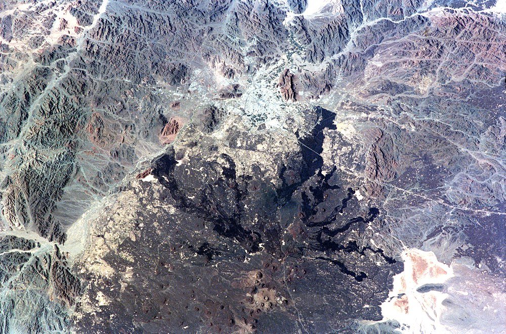 Flygfoto av vulkankrater och berg Flygfoto av en vulkankrater omgiven av robust bergsterräng och gles vegetation