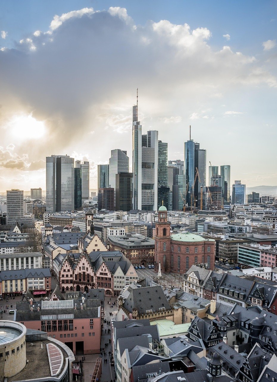 Stadssilhuett av Frankfurt am Main med moderna skyskrapor och historiska byggnader under en molnig himmel vid solnedgången