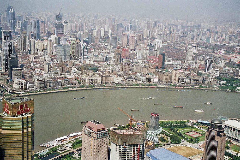 Flygfoto av Shanghais stadssilhuett med Huangpu-floden och många höghus och båtar på vattnet