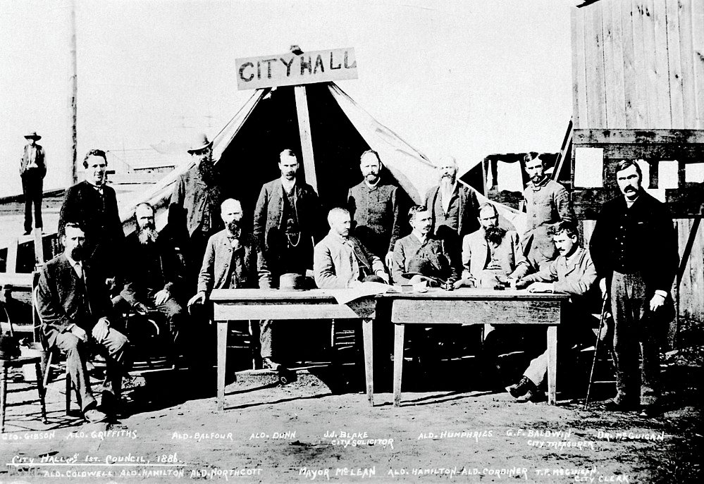 Stadshusets Första Rådsmöte 1886 Historiskt svartvitt foto av Stadshusets första råd 1886 med män i kostymer och ett tält märkt Stadshus