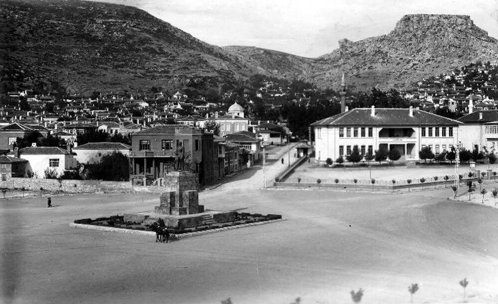 Historiskt torg med staty och berg Historiskt svartvitt foto av ett torg med en staty, traditionella byggnader och bergig bakgrund