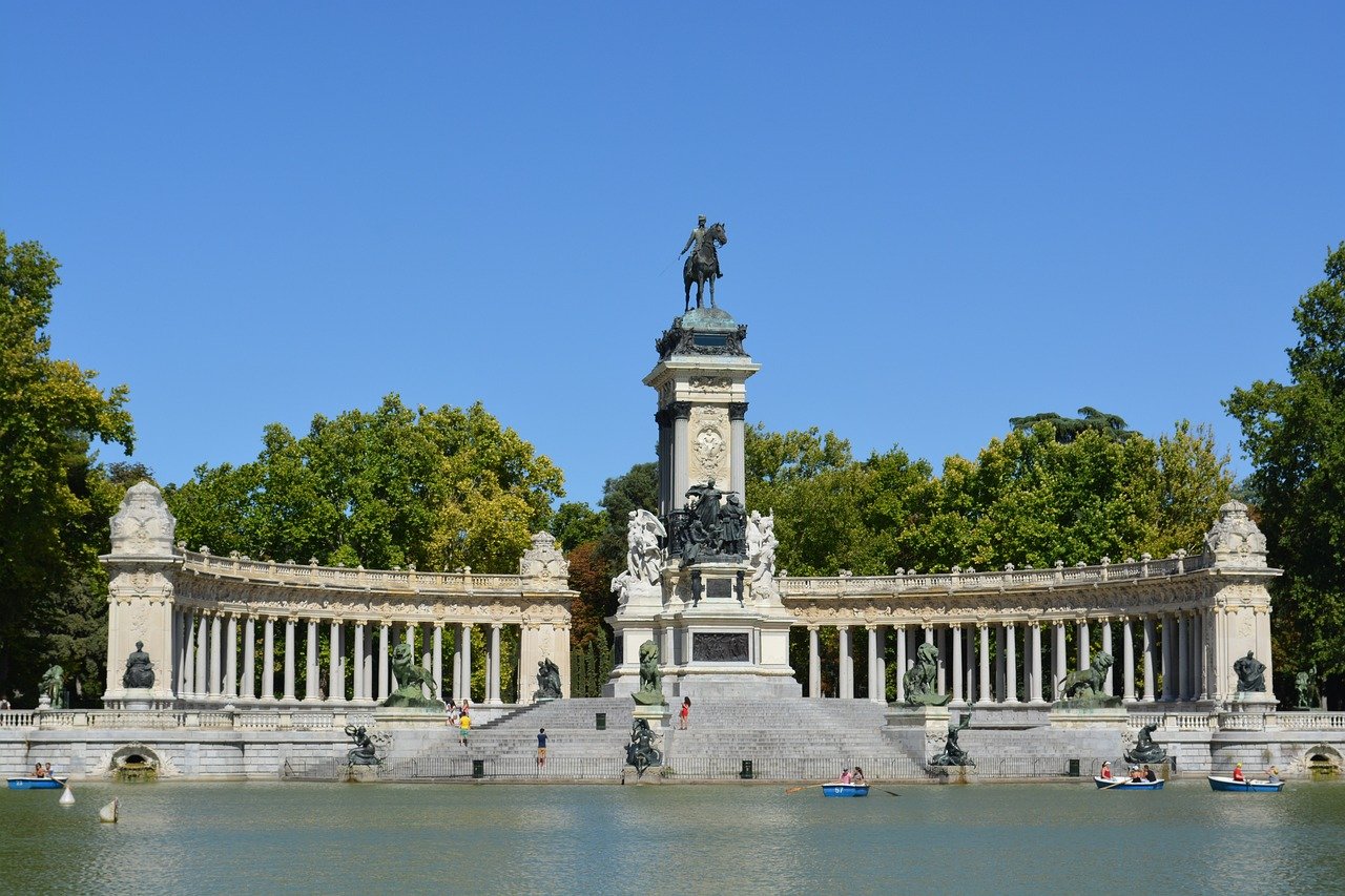 Monument med ryttarstaty och kolonnad i Retiroparken i Madrid med människor som ror på sjön