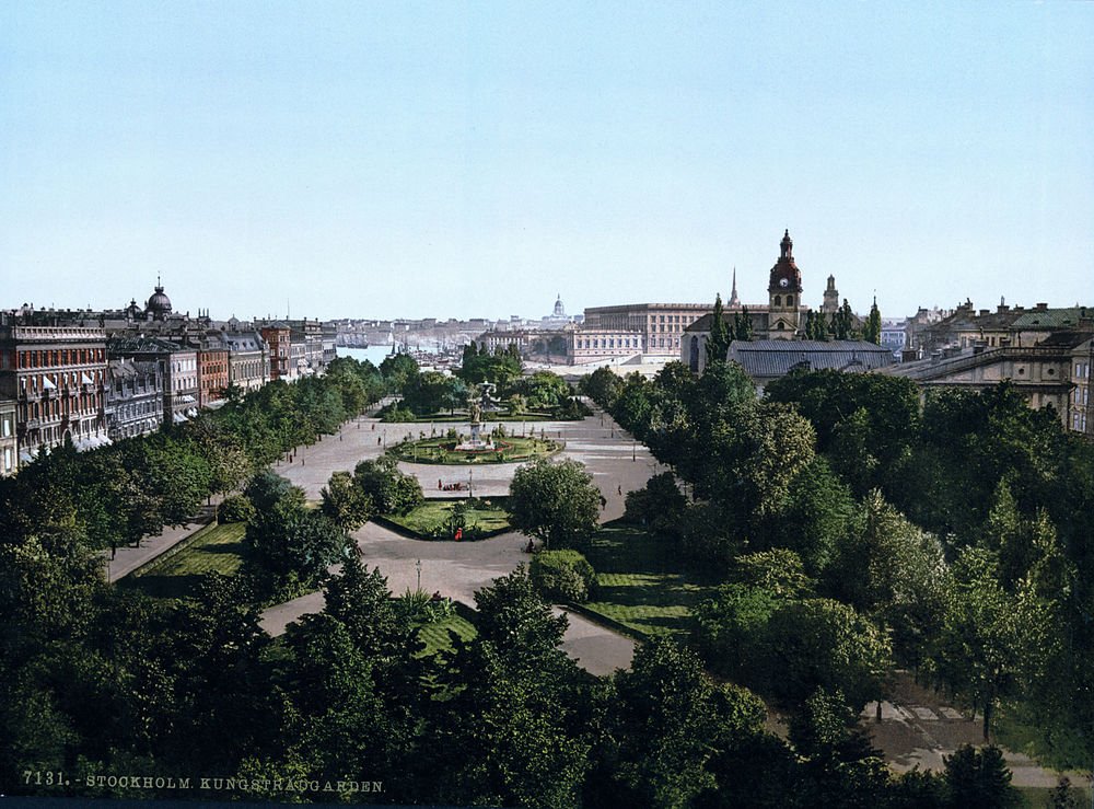 Kungsträdgården i Stockholm med historiska byggnader Scenisk vy över Kungsträdgården i Stockholm med frodig grönska, historiska byggnader och klarblå himmel